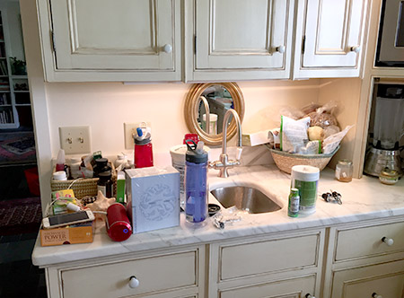 Before the KonMari Method, my marble kitchen counter is covered in knickknacks, vitamin bottles, 2 different waterbottles, and other clutter.